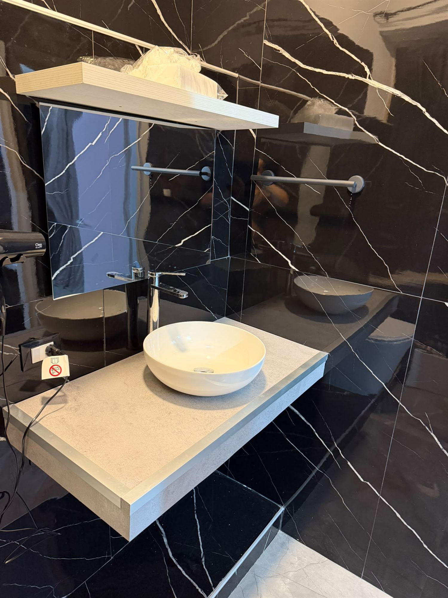 Lavabo in ceramica su mensola, pareti in marmo nero