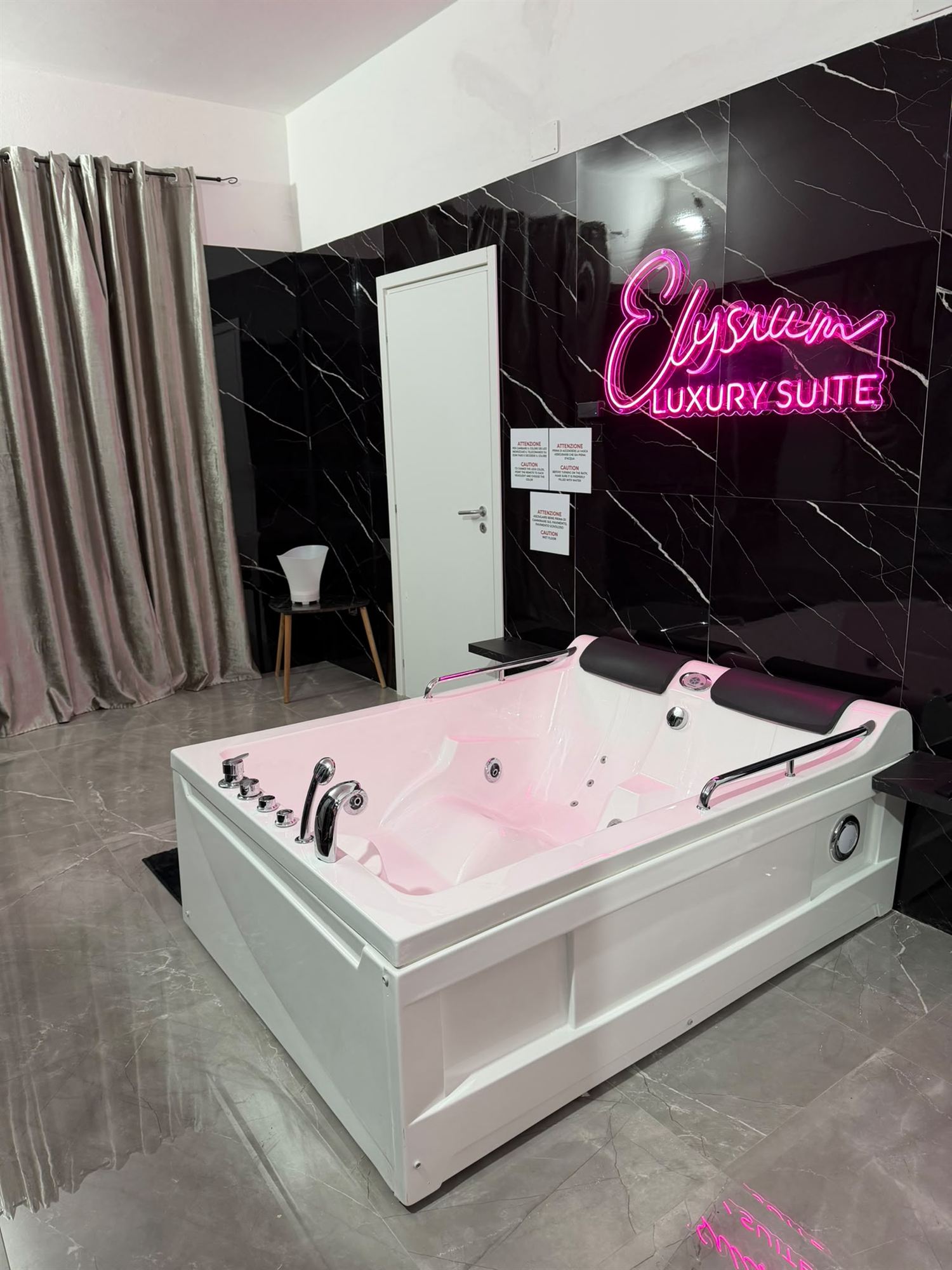 Vasca idromassaggio con insegna neon Elysium Luxury Suite
